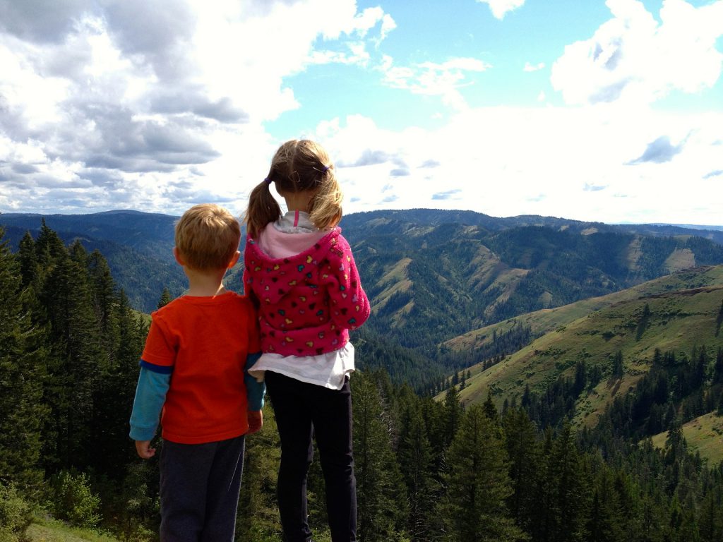 Deux enfants de dos regardent le paysage à la montagne