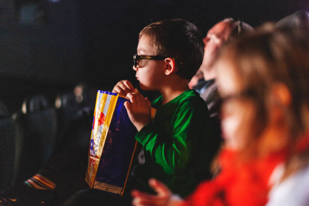 Petit garçon au cinéma, avec des lunettes 3D et un pot de popcorn