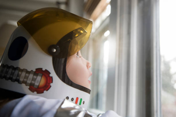 Petite fille dans un costume d'astronaute qui regarde par la fenêtre