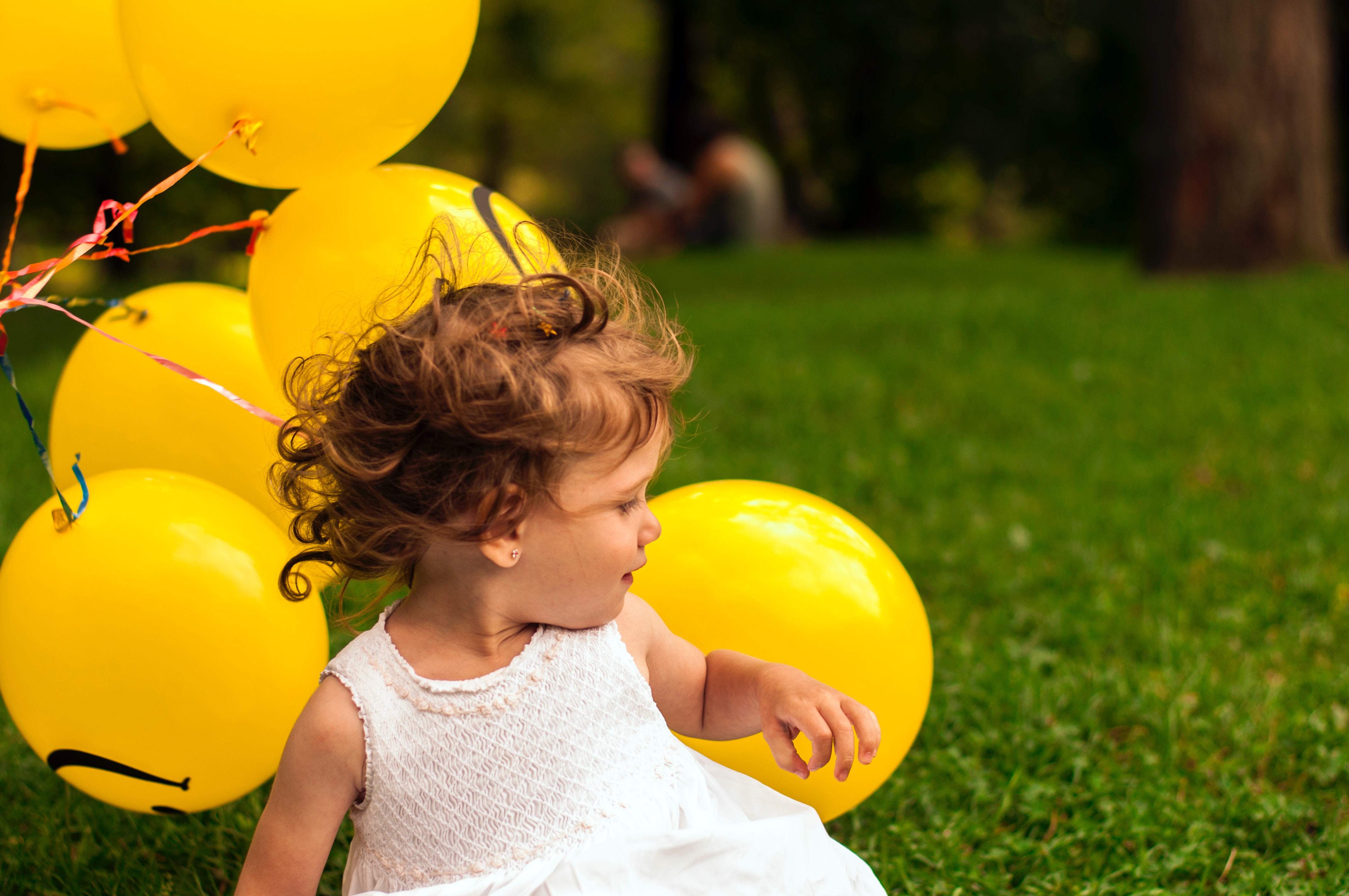 Petite fille en train de jouer dans l'herbe avec des ballons jaunes