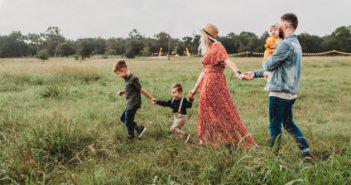 Famille de trois enfants qui marche dans un champ