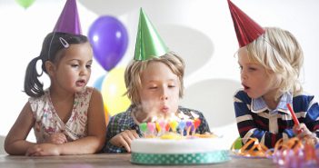 Enfant qui souffle ses bougies d'anniversaire avec ses amis